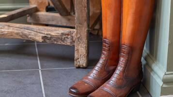 A pair of brown leather boots leaning against a wall.