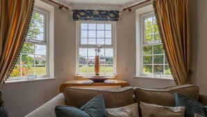 A cozy room with a large window, a wooden bench, and a vase with a plant. - Harmony House (York)