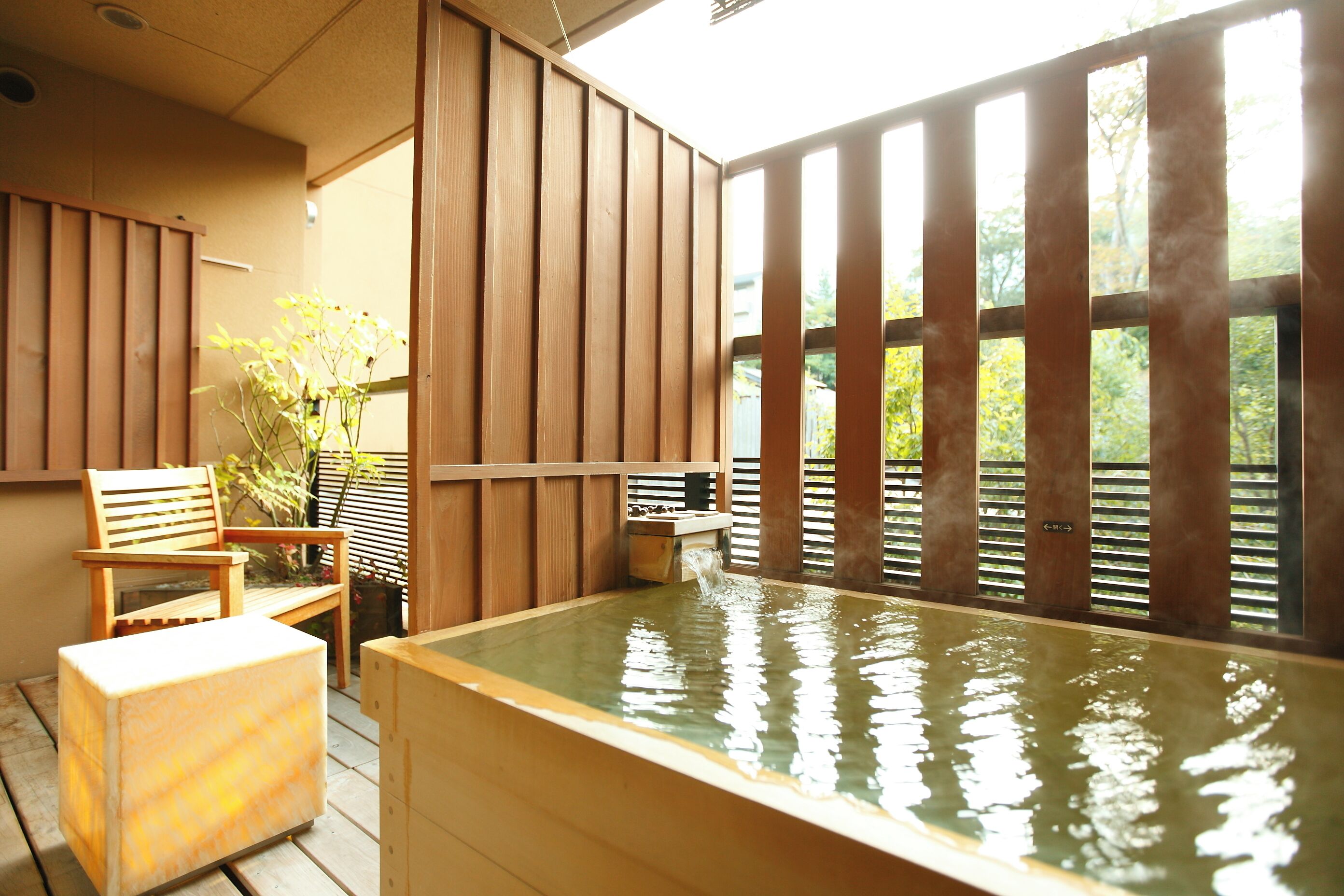 Un onsen japonés tradicional con puertas correderas de madera, un banco de madera y un baño termal.