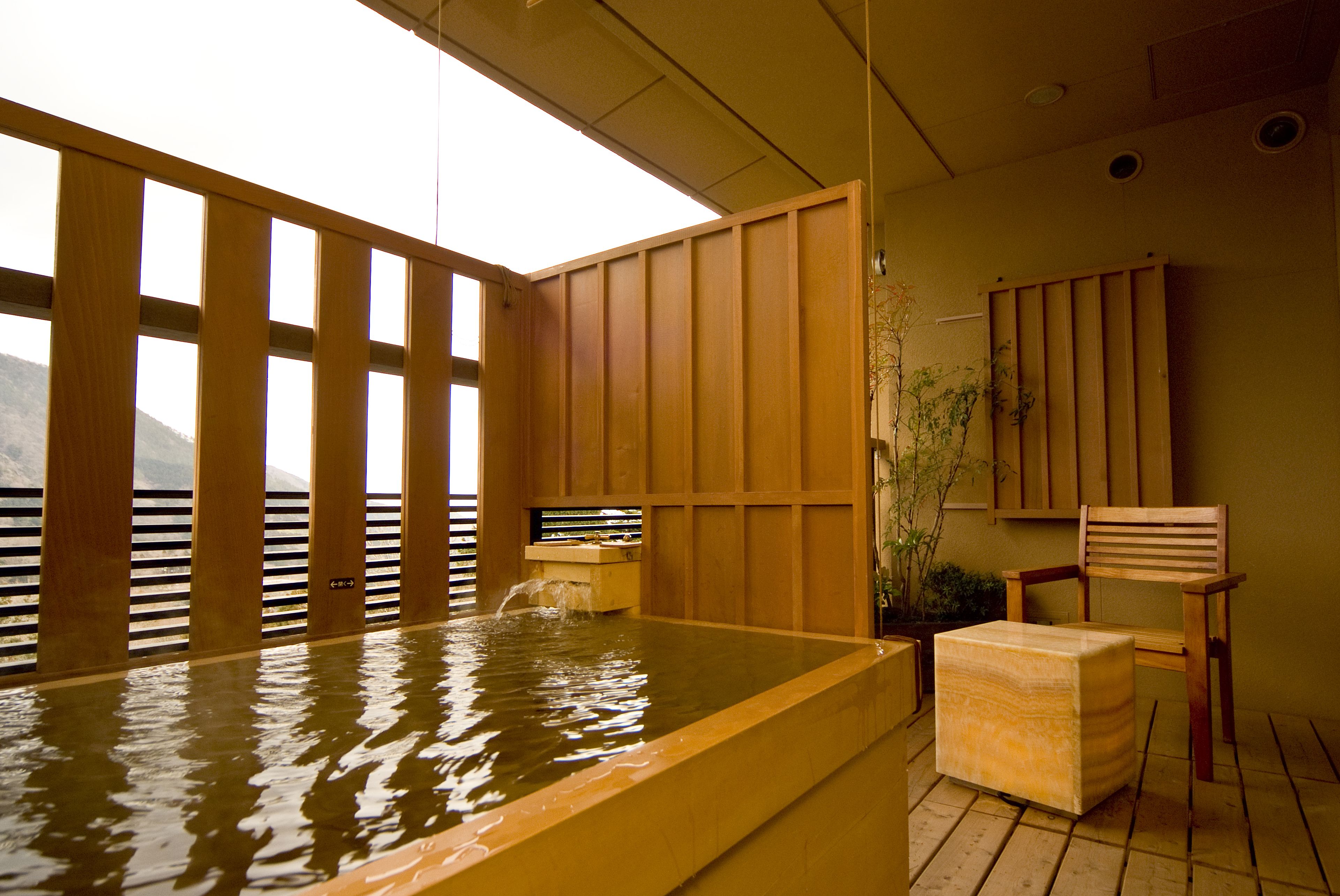 Uma onsen japonesa tradicional com portas de correr de madeira, um banco de madeira e uma pequena mesa de madeira.