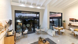 A modern interior with a dining area, a kitchen, and a large glass door leading to an outdoor space. - THEBLOEM Guest Suites by Knysna Paradise Collection (Knysna)