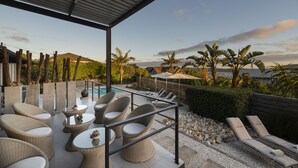 A covered outdoor seating area with wicker furniture and a pool in the background. - THEBLOEM Guest Suites by Knysna Paradise Collection (Knysna)