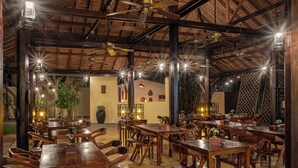 A restaurant with wooden tables and chairs, ceiling fans, and hanging lights. - Pavillon d'Orient Boutique (Siem Reap)