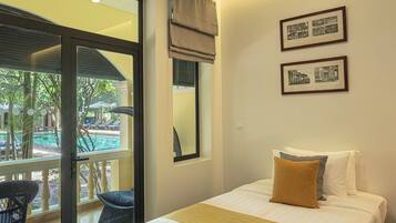 Une chambre d’hôtel avec un lit, une vue sur la piscine et deux tableaux encadrés au mur.