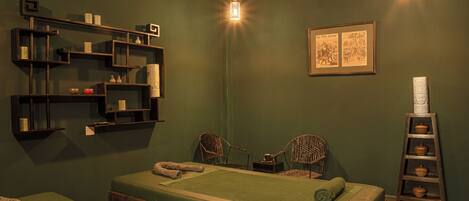 A room with a bed, two chairs, a shelf with items, a ladder with bowls, and a framed picture on the wall.