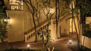A well-lit outdoor staircase surrounded by trees and plants, leading to a building with a balcony. - Pavillon d'Orient Boutique (Siem Reap)