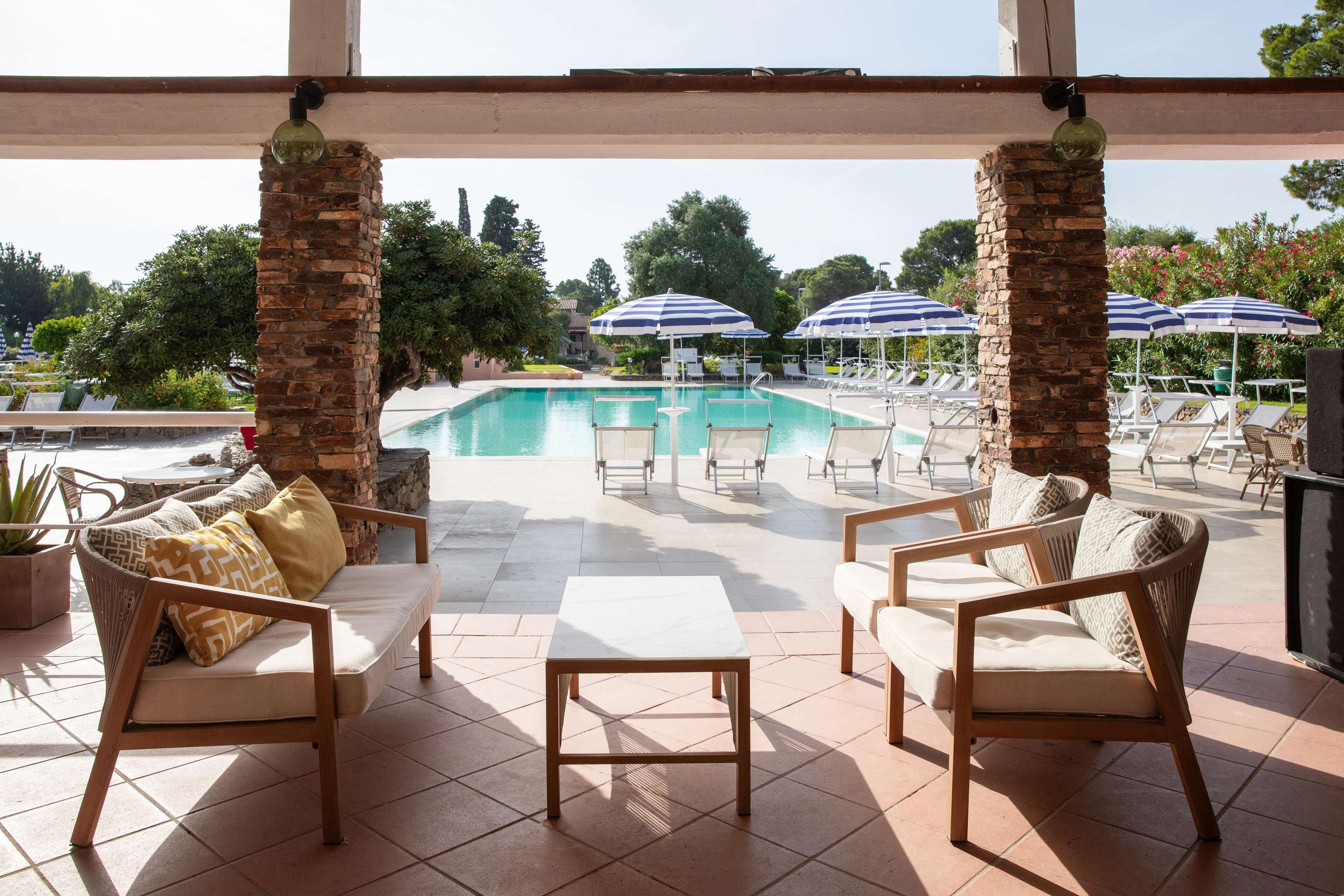 A poolside area with lounge chairs, umbrellas, and a view of the pool.