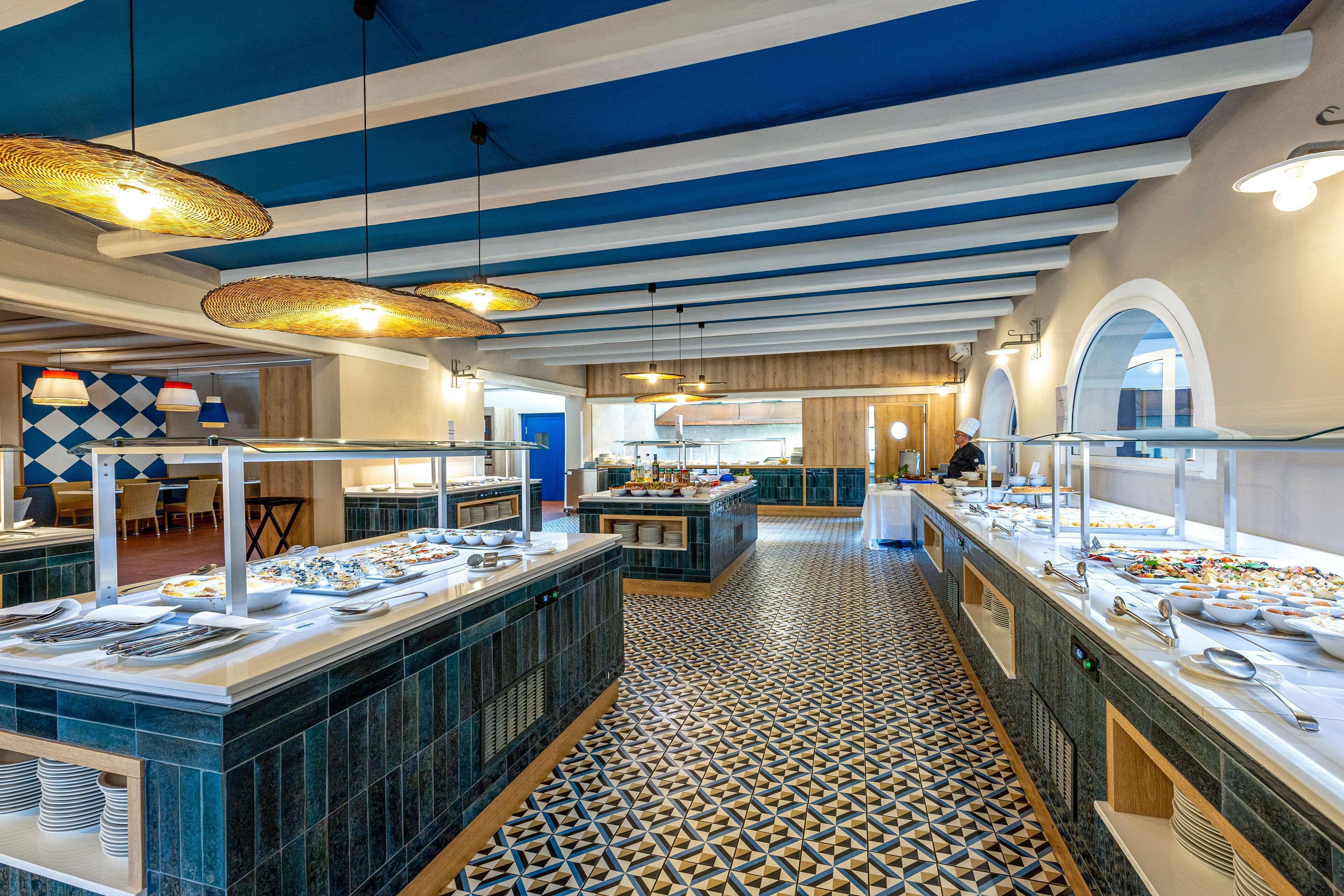 A buffet area with multiple serving stations, a patterned floor, and blue and white striped ceiling.