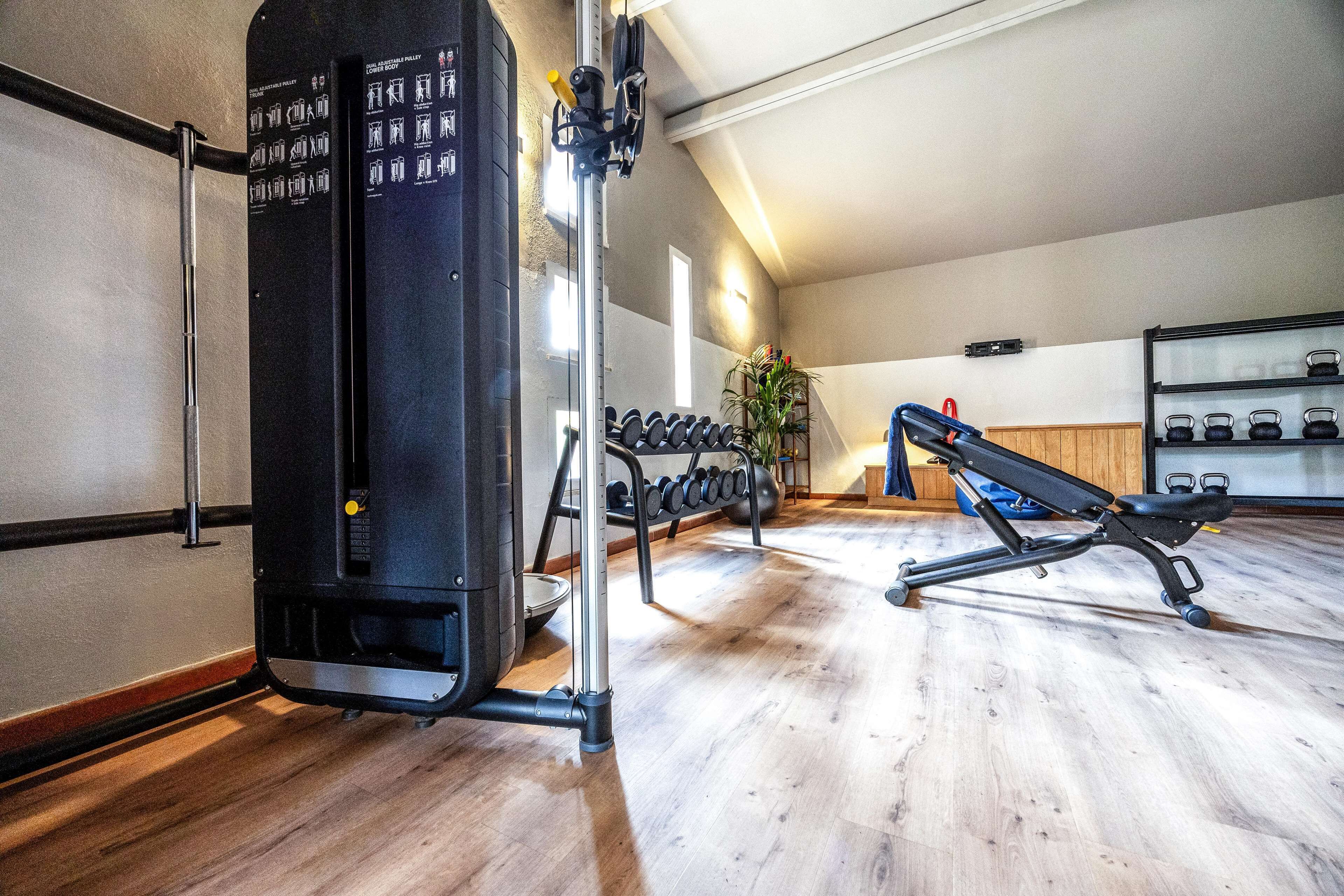 A gym with weight machines, a bench, and a rack of dumbbells.