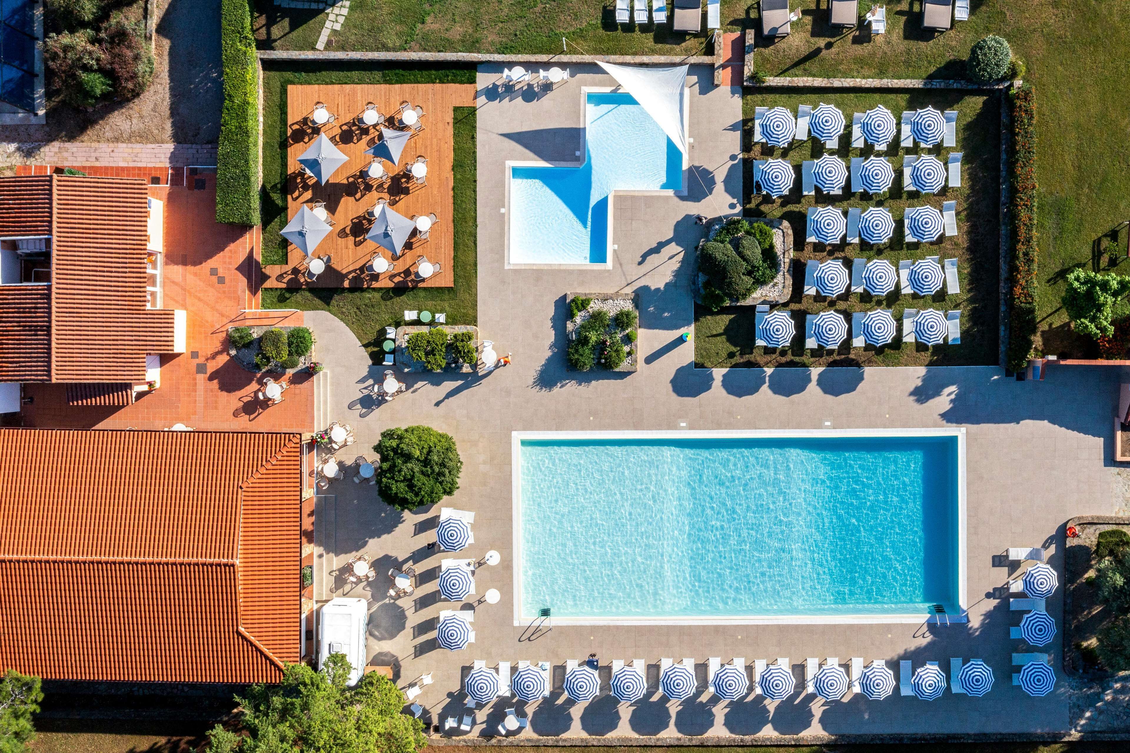 Vue aérienne d’un hôtel doté d’une grande piscine, d’espaces de détente en plein air et d’un jardin bien entretenu.