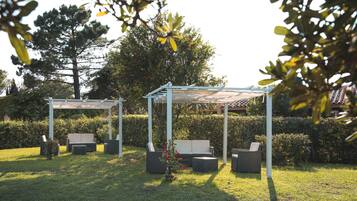 An outdoor seating area with a pergola, cushioned chairs, and a small table.