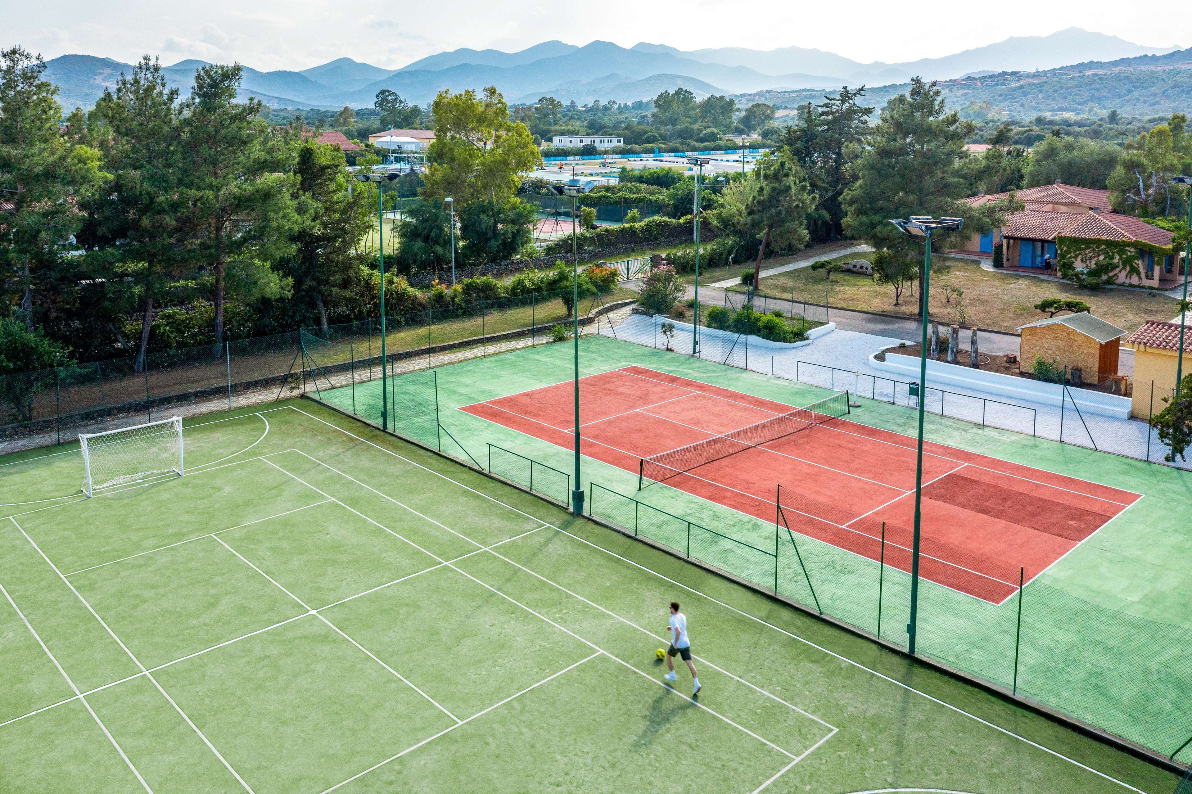 En tennisbane med net, omgivet af træer og bygninger.