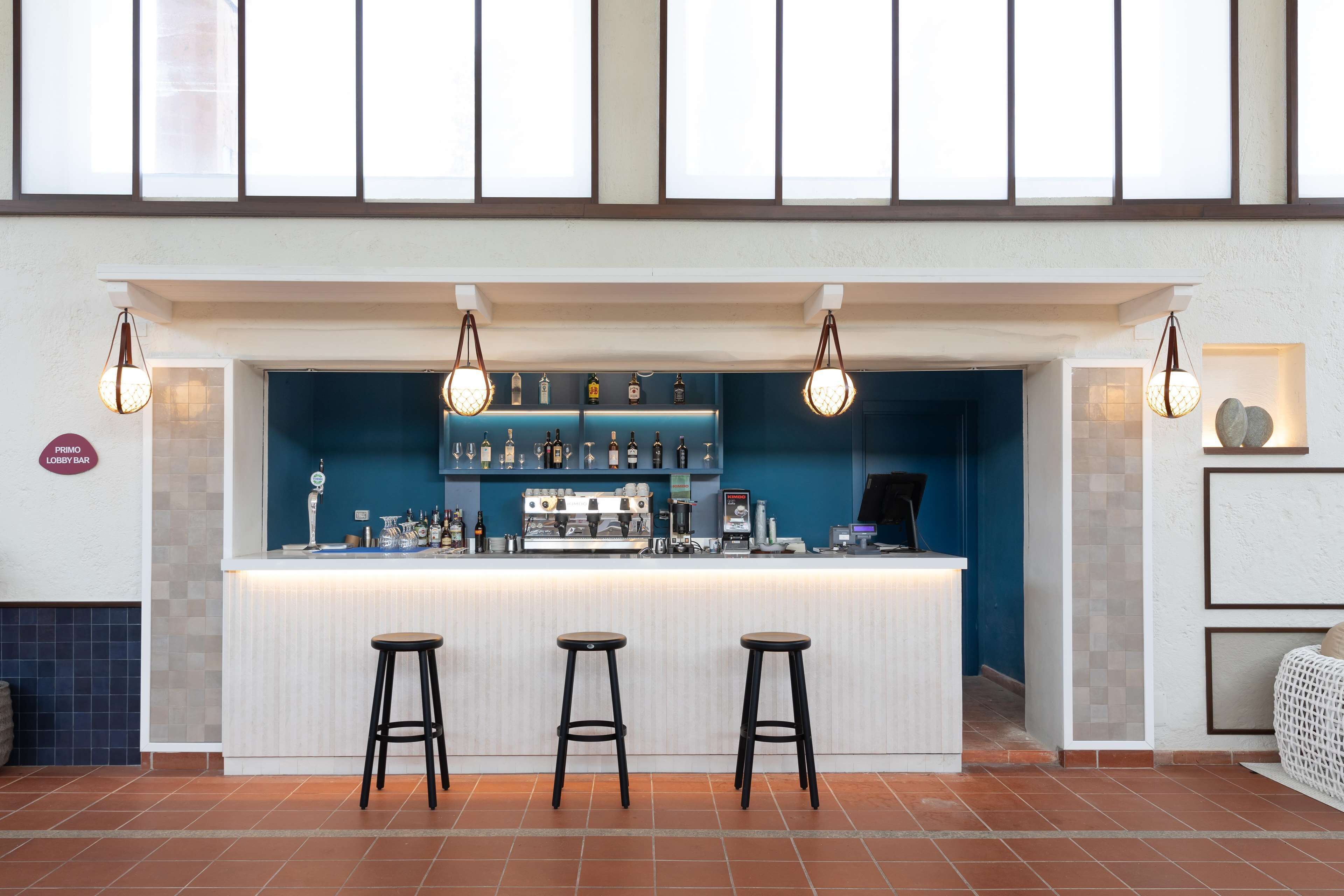 A bar area with stools, a counter, and a selection of bottles and glasses.
