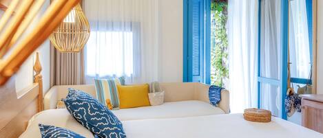 A hotel room with two beds, a large window with blue shutters, a wicker basket, and a straw hat on the bed.