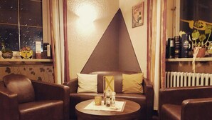 A cozy living room with a brown leather sofa, a coffee table with a decorative item, and a window with curtains. - Hotel Restaurant Dragoner (Peiting)