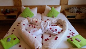 A double bed with rose petals and towels arranged in a heart shape. - Hotel Restaurant Dragoner (Peiting)
