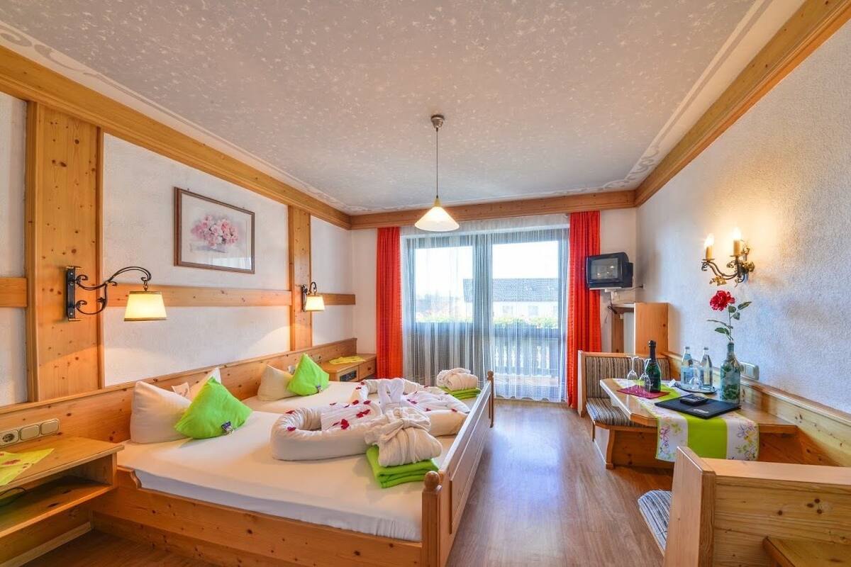 Una habitación de hotel acogedora con una cama de madera, un escritorio, una silla y un televisor.