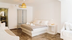 A modern bedroom with a large bed, bedside tables, a wardrobe, and a bathroom visible through an open door. - Pension George (Santorini)