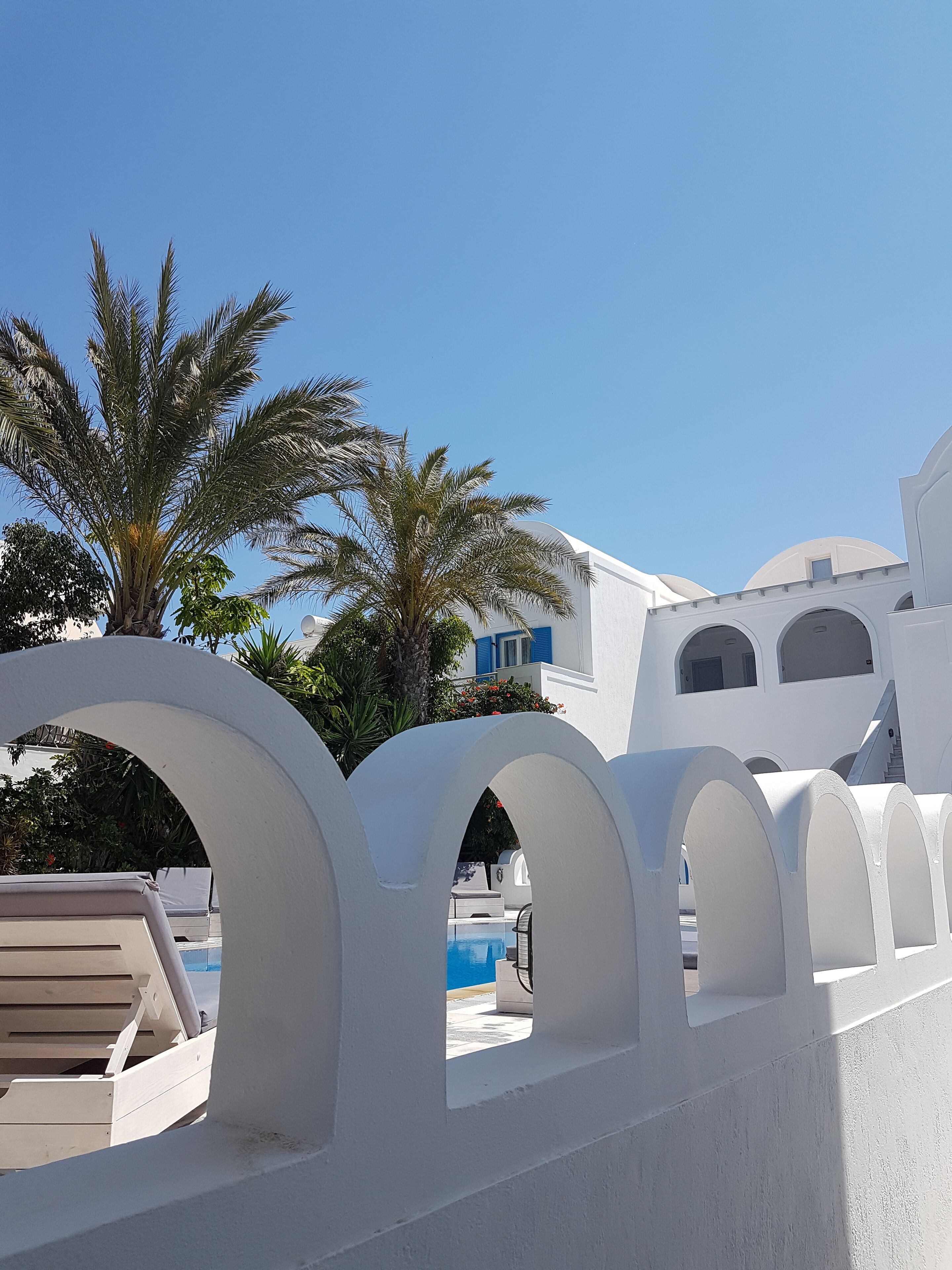 A white building with arched windows and a pool area.