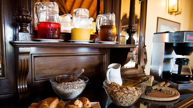 Ein Frühstücksbuffet mit Croissants, Müsli und Kaffee auf einer Holzauslage.