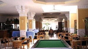 A billiards room with a pool table, wooden chairs, and tables with blue tablecloths. - Hôtel Solymar Beach (Soliman)