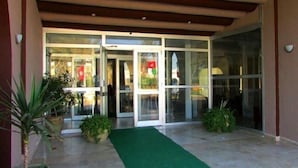 A building entrance with a glass door, a green carpet, and potted plants. - Hôtel Solymar Beach (Soliman)
