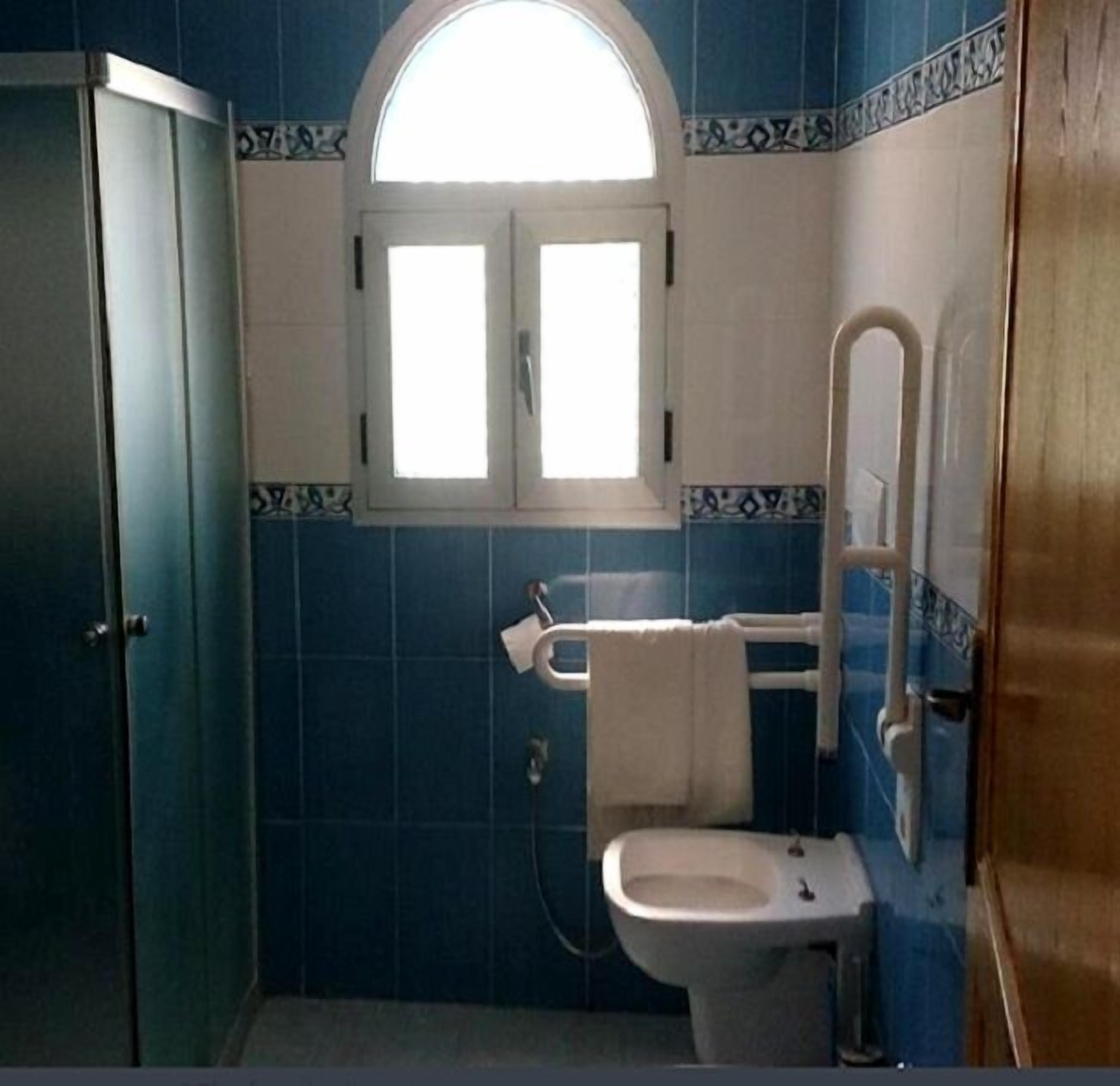 A bathroom with a toilet, a window, and a shower area.