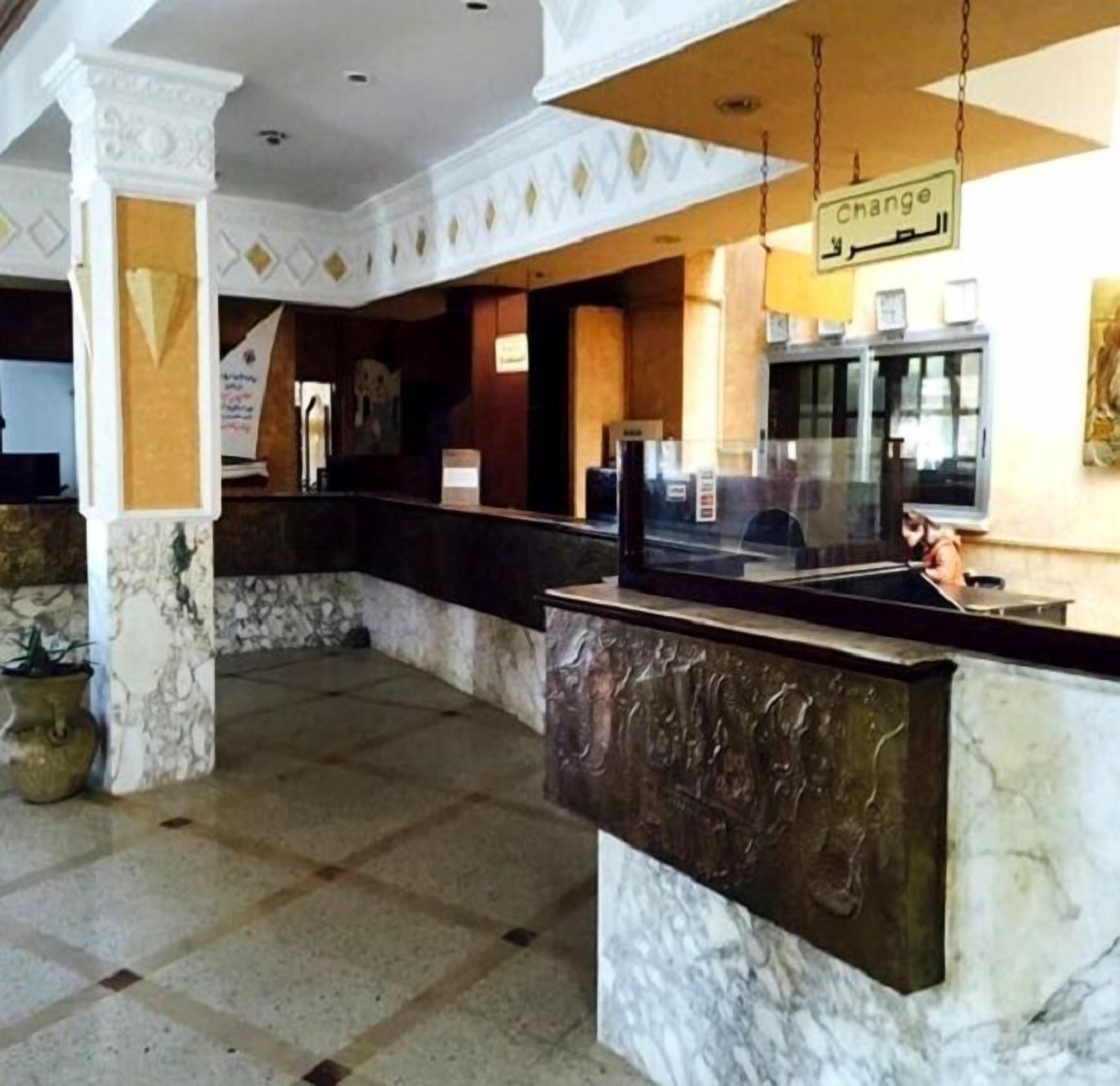 A lobby with a marble reception desk, a 'change' sign, and a glass partition.