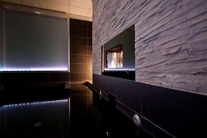 A modern spa area with a stone-textured wall, a large mirror, and a sleek black floor. - Hotel Selfoss (Selfoss)