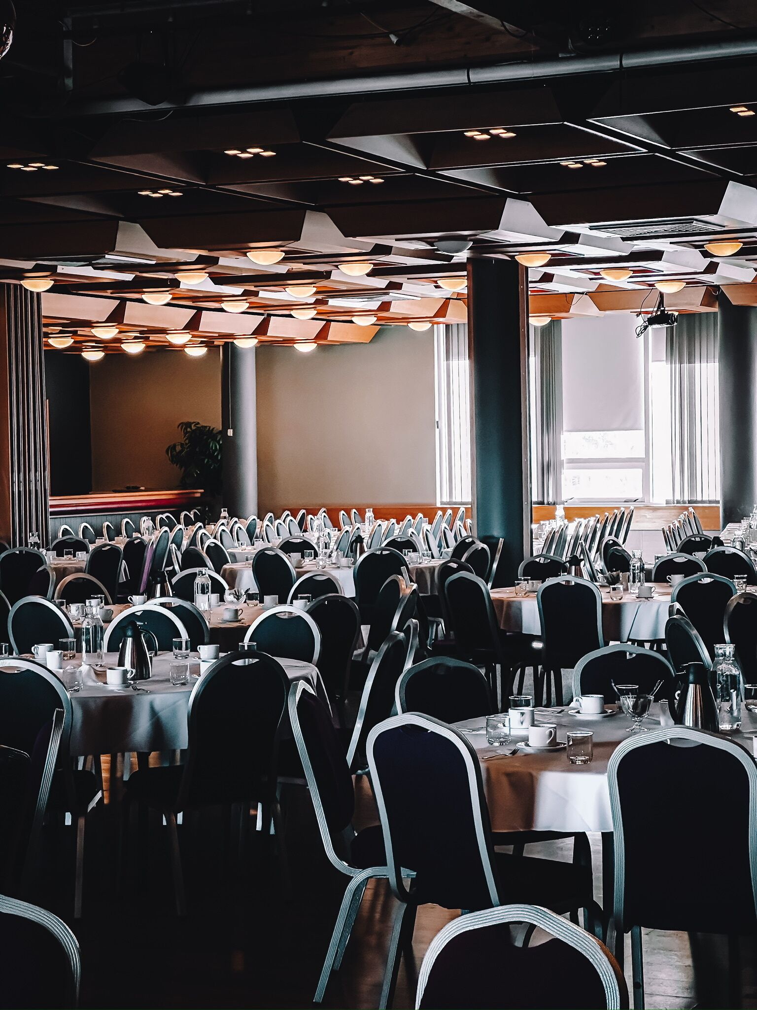 A large conference room with multiple tables and chairs, equipped with nameplates and table settings.