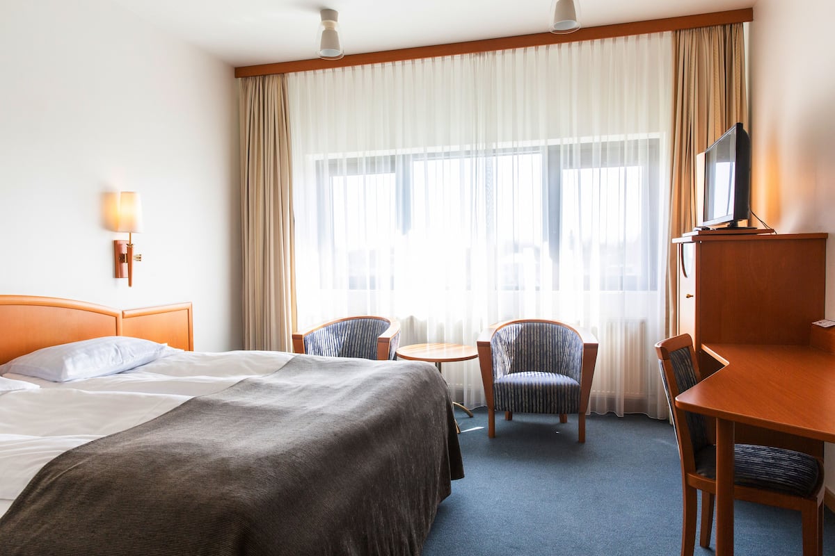 Habitación de hotel con cama, dos sillones, una mesita, escritorio y televisión.