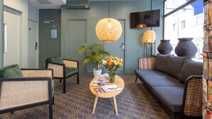 A modern lobby with seating areas, a large window with a view, and a flat-screen TV mounted on the wall. - Hotel de Paris (Boulogne-Billancourt)