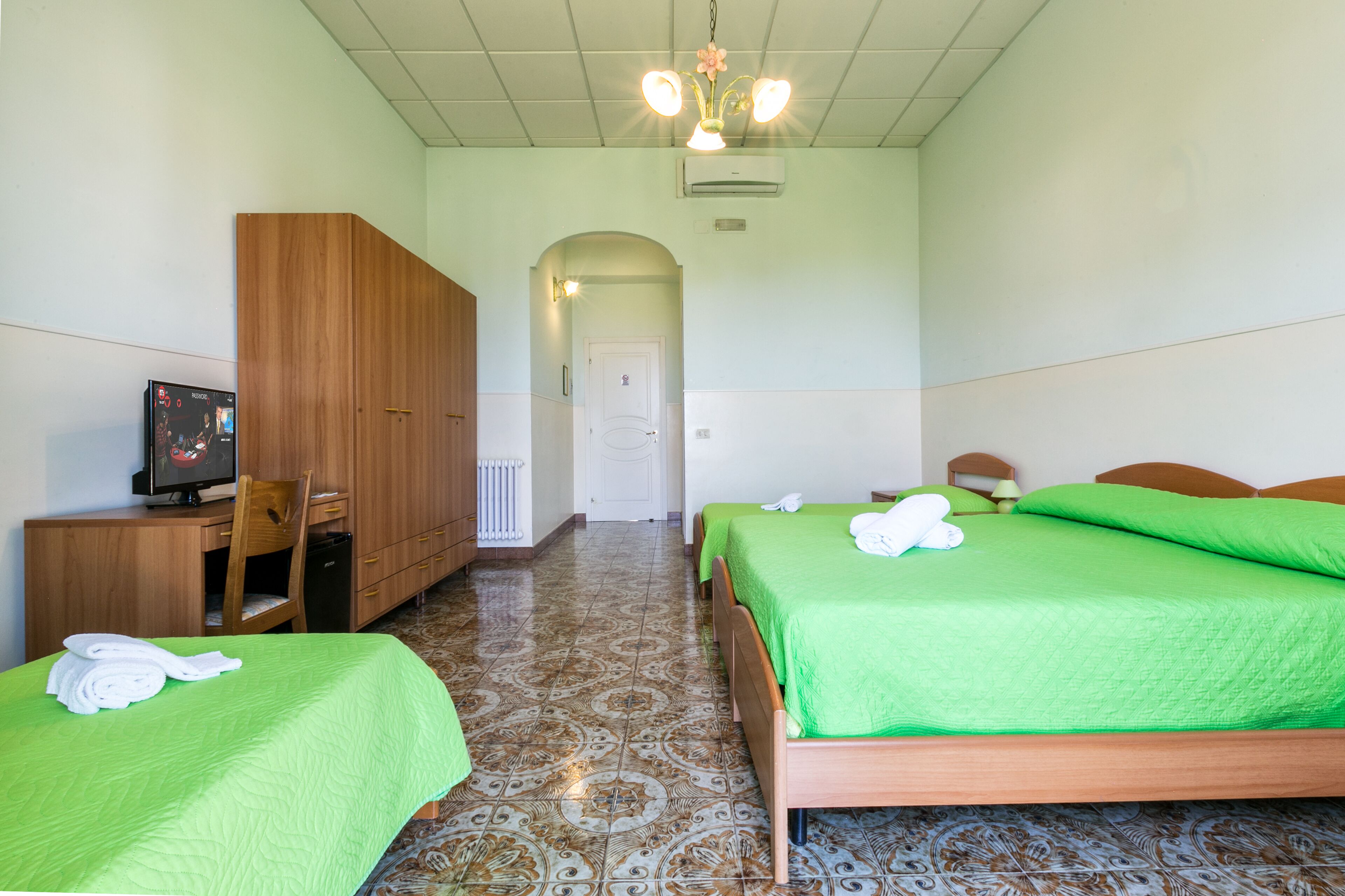 A hotel room with two beds, a desk, a television, and a wardrobe.