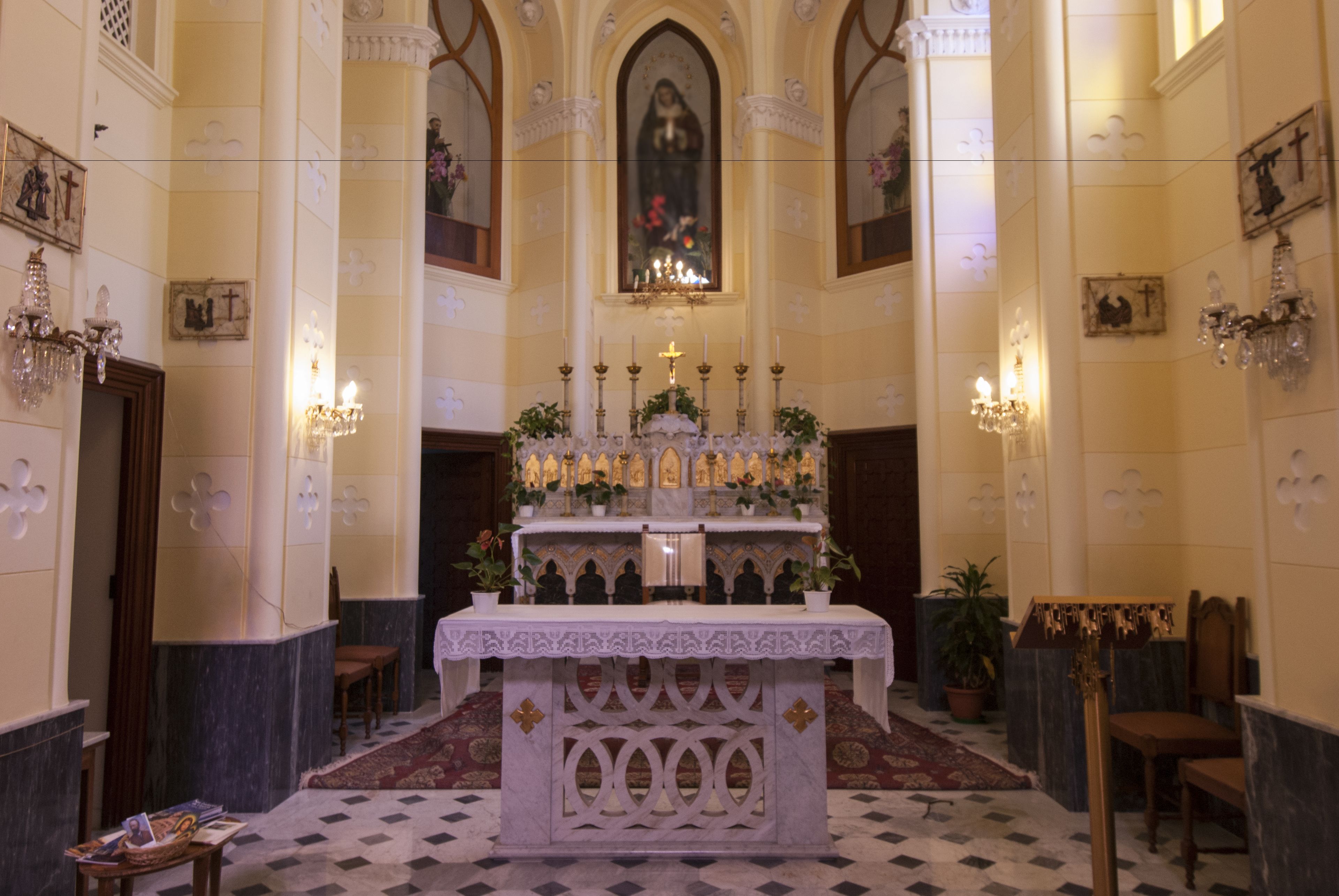 Ett utsmyckat altare med ljus och blommor, omgivet av stolar och en mönstrad matta.