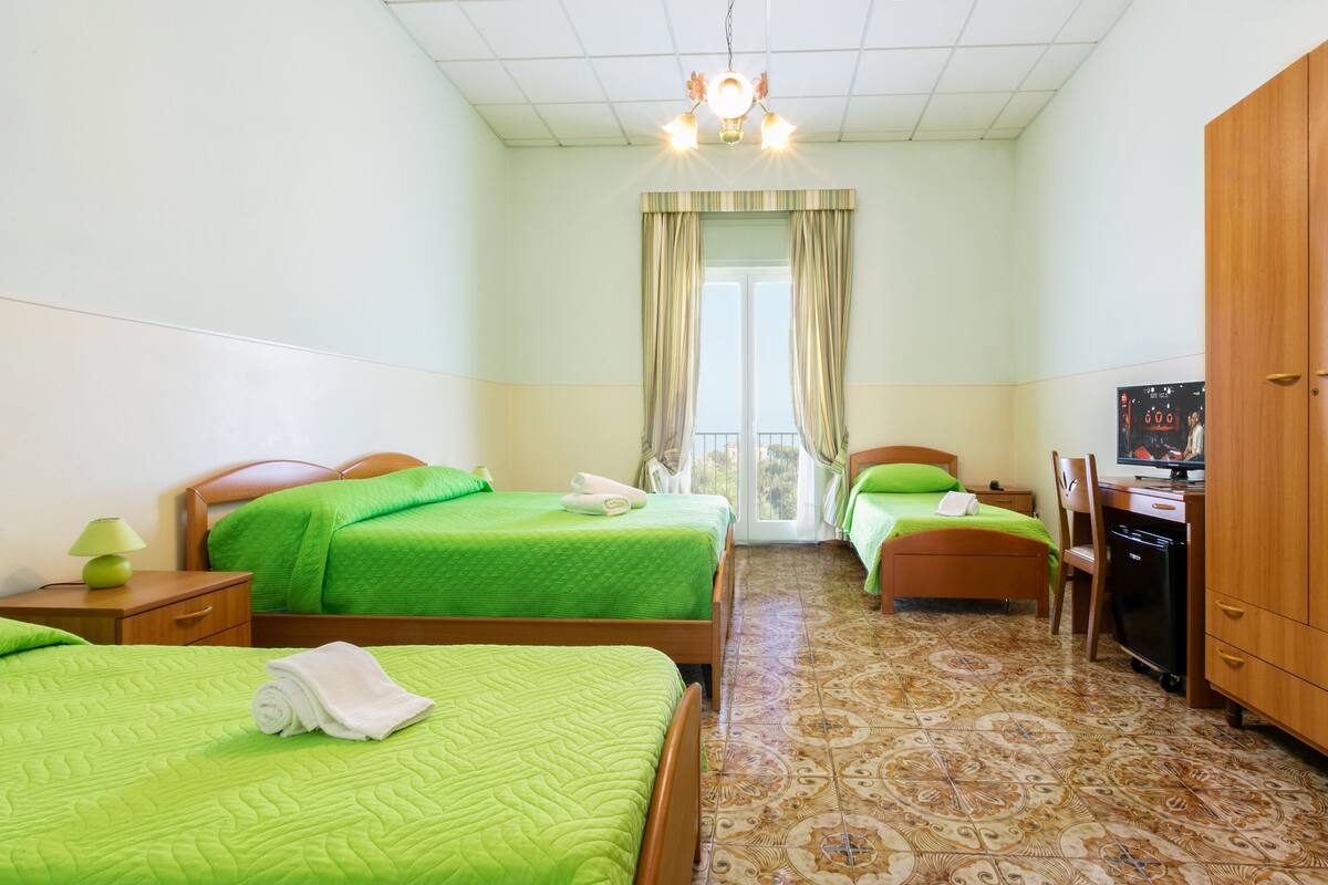 Ein Hotelzimmer mit zwei Betten, einem Schreibtisch, einem Fernseher und einem Kleiderschrank.