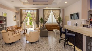 Una sala de estar moderna con sofá, sillones, una mesa de centro y una zona de bar con televisor y taburetes.