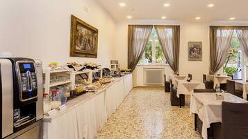 Un comedor de hotel con un sistema de bufé, una máquina de café y obras de arte en las paredes.