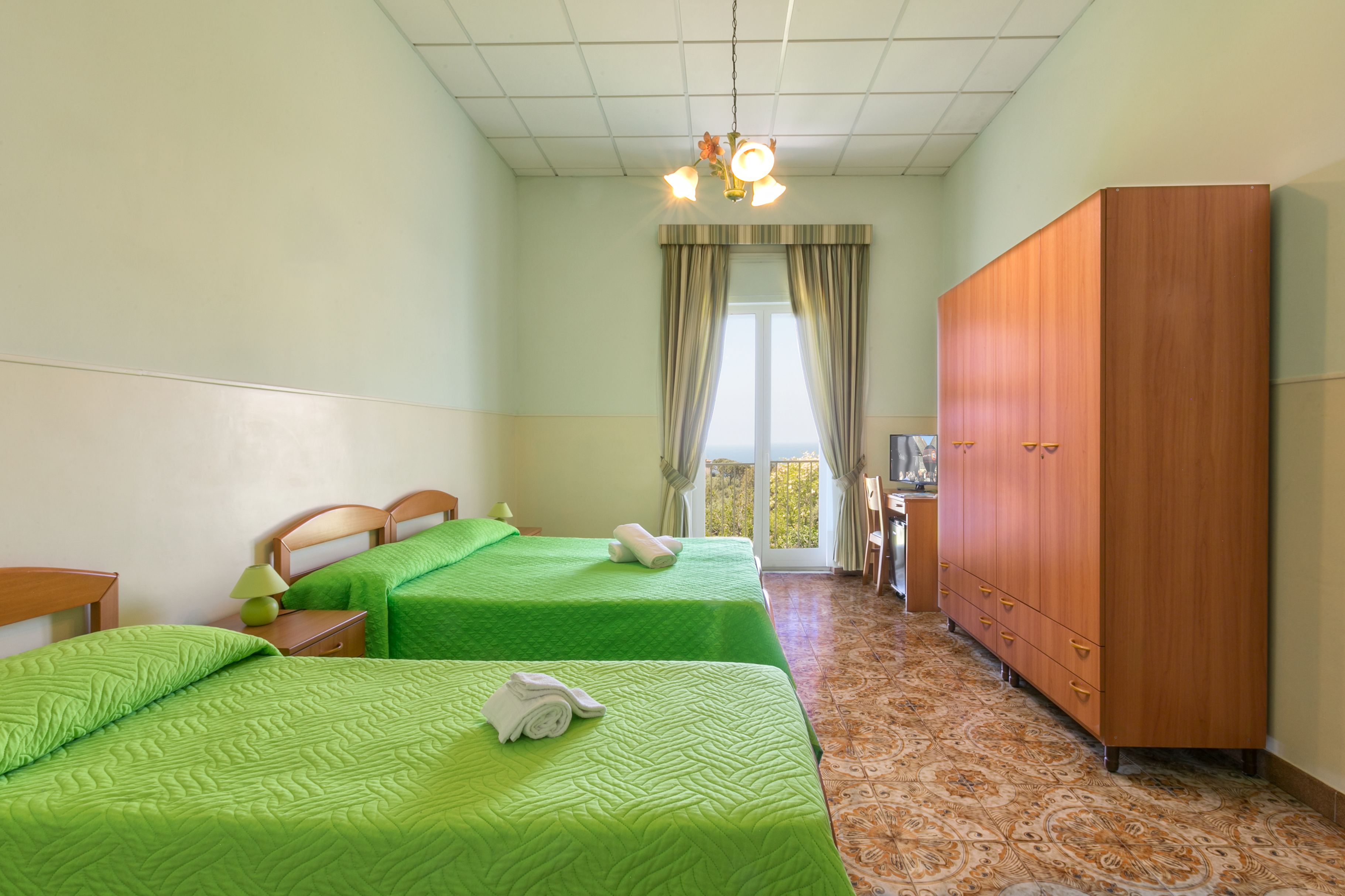 Une chambre d’hôtel avec deux lits, une armoire, un bureau et une vue sur l’extérieur.