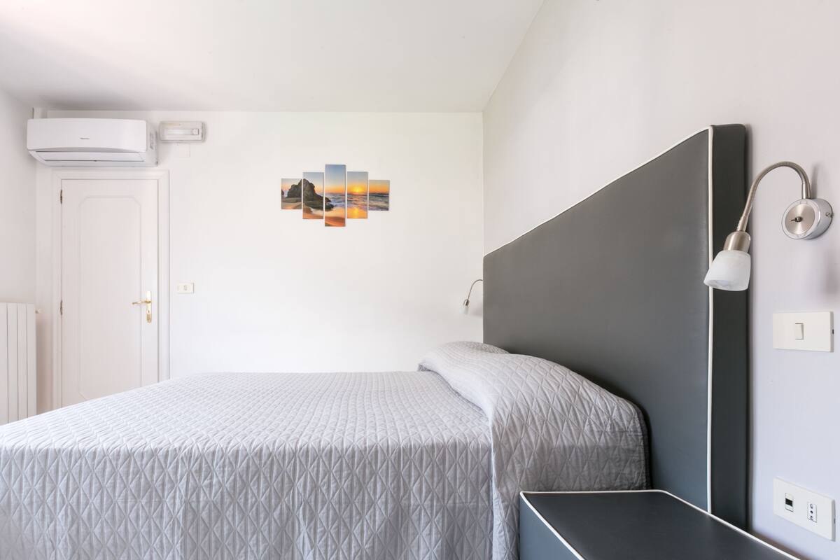 Ein modernes Schlafzimmer mit Bett, Nachttisch und einer Wandleuchte.