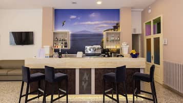 Eine Bar mit Marmorplatte, zwei Barhocker, einem Fernseher und einer Aussichts mural mit Meereslandschaft und einem Vogel.
