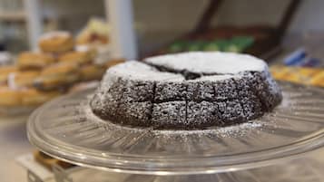 A chocolate cake on a glass plate with powdered sugar on top.