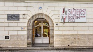 El exterior del hotel SITTERS, con una entrada de arco de piedra, un cartel y una placa en la pared.