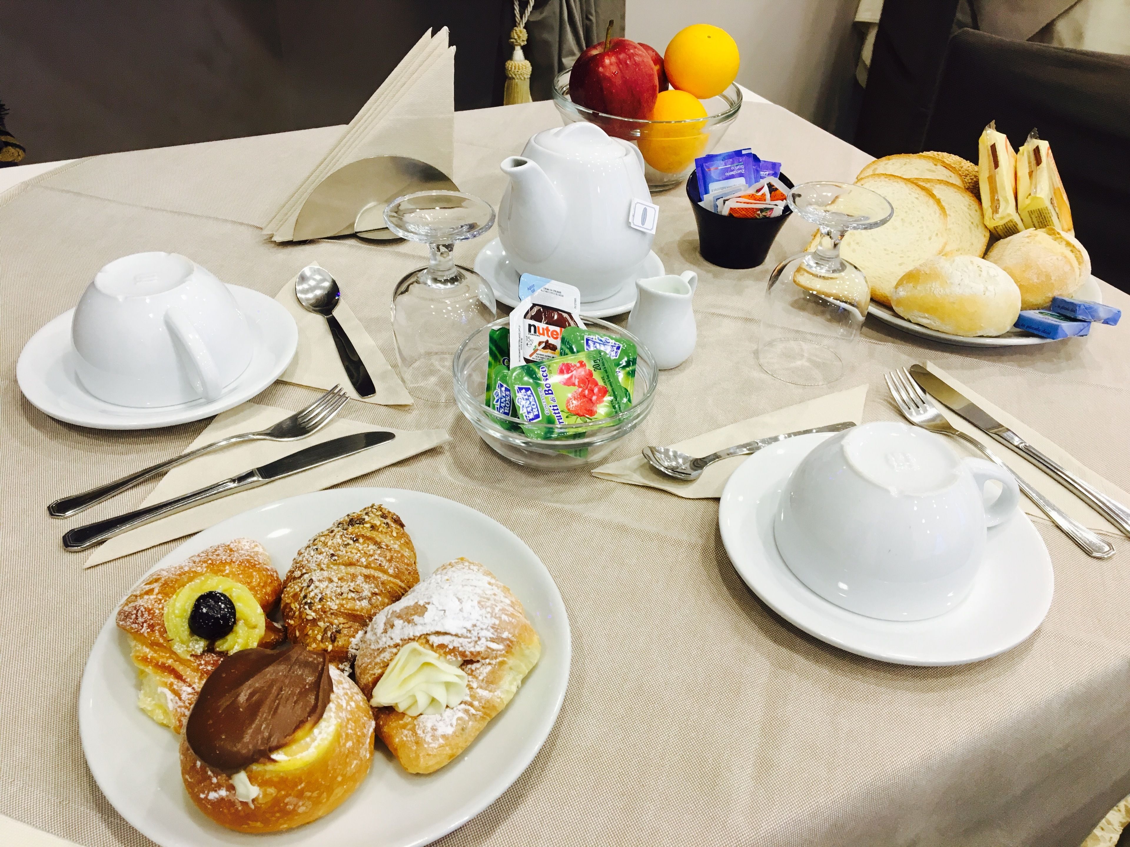 A breakfast table with pastries, fruits, and tea.
