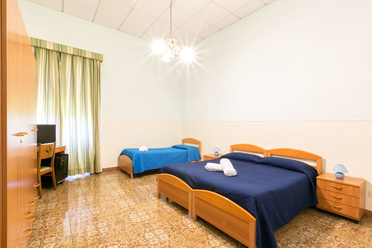 Ein Hotelzimmer mit zwei Betten, einem Schreibtisch und einem Sessel.