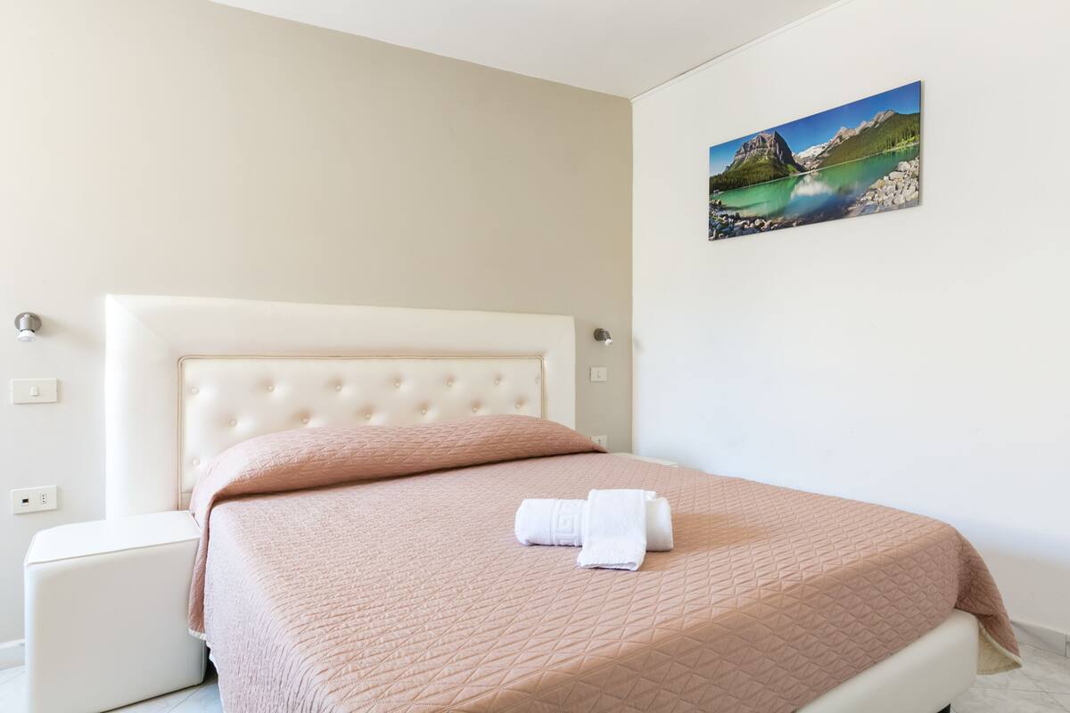 Ein Schlafzimmer mit einem Bett, einem Nachttisch und einem Wandbild.