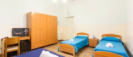 A hotel room with two beds, a desk with a computer, a wardrobe, and a television.