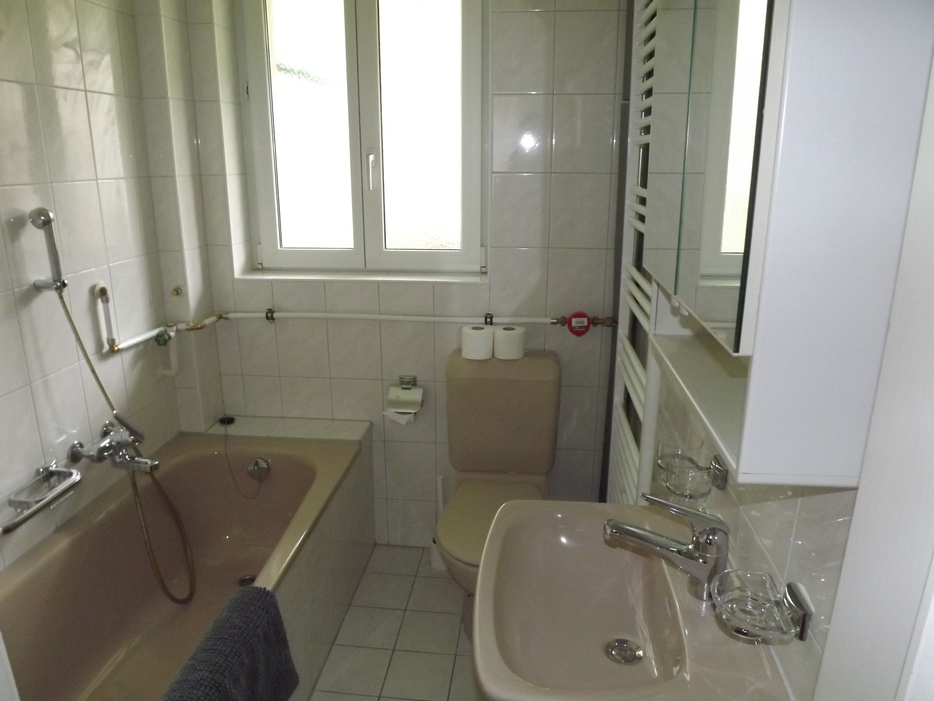 Ein Badezimmer mit Badewanne, Toilette, Waschbecken und Fenster.