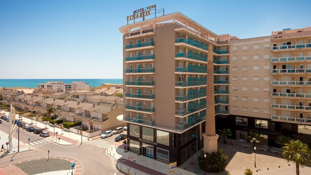 Et hotel med flere altaner, fri udsigt til stranden, og et skilt med teksten "HOTEL THE VINAROS".