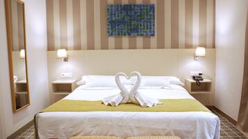 Habitación de hotel con una cama, dos mesitas de noche, un espejo, una obra de arte en la pared y un suelo estampado.