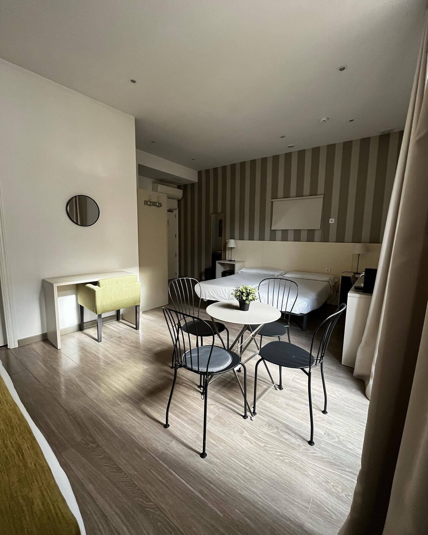 A modern hotel room with a dining area, a bed, and a bathroom.